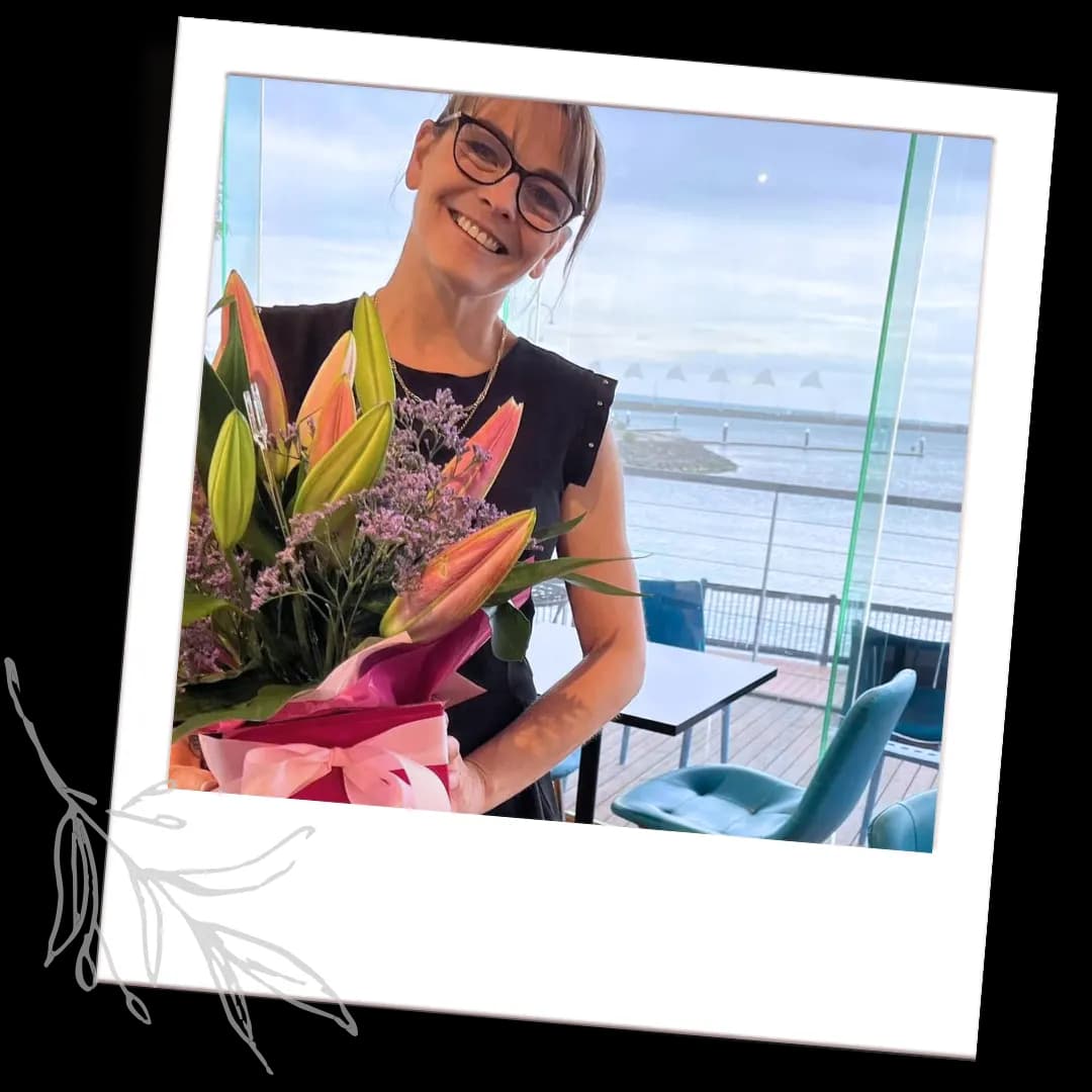 Kelly Edwards, owner of Bayside Cafe, holding a bouquet of flowers by the harbour